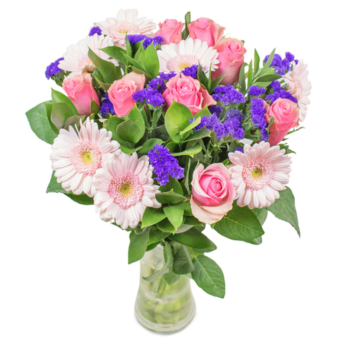 A vibrant, elegantly designed floral bouquet prepared by Romford Flowers, positioned in a clear glass vase on a pure white backdrop-a hallmark of Romford's floral artistry. At its heart, seven to nine medium-pink roses with tightly furled or gently opening petals create a focal point suggestive of classic sophistication. These are framed by five to seven delicate pale pink gerbera daisies, their round, radiant faces echoing the brightness of Main Road's bustling storefronts. Deep purple statice, placed thoughtfully among the blooms, offers both textural intrigue and vivid colour contrast, reminiscent of lively displays found at Romford Market. Lush green foliage forms a vibrant, organic base, enhancing the arrangement's sense of abundance while recalling the verdant energy of Hillside Road. The crystal vase, its water and stems clearly visible, highlights the bouquet's freshness and handcrafted composition. Suitable for birthdays, anniversaries, Mother's Day, or to bring cheerful beauty into a local office or home, this bouquet is a true celebration of Romford's spirit-infused with affection and a sense of joyful occasion.
